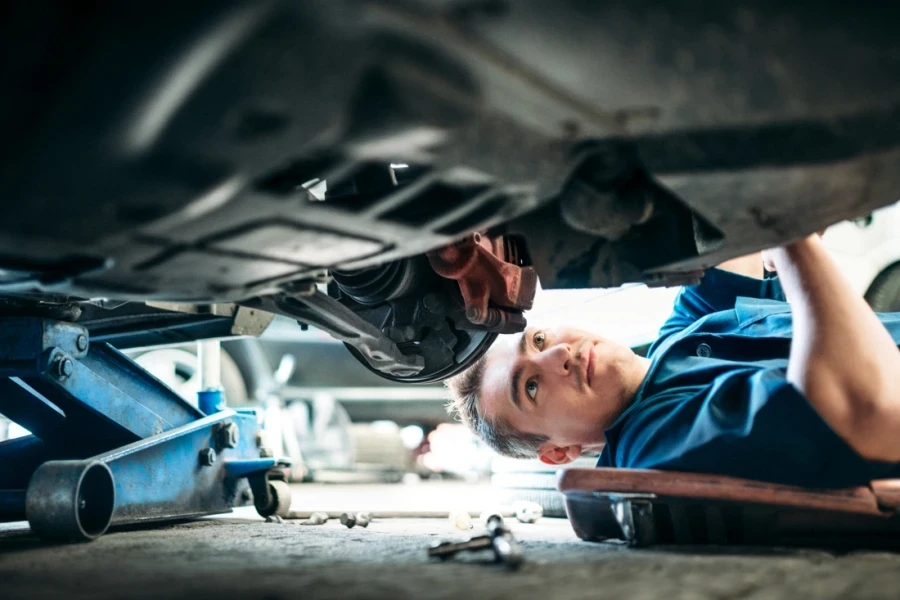 Car mechanic working under a vehicle