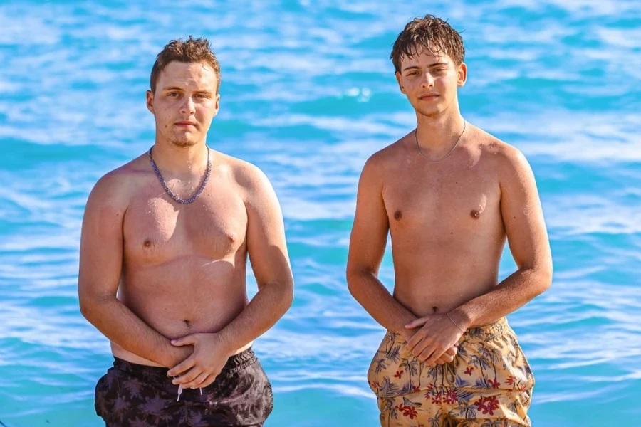 Caucasian teenage male friends showing off their muscular build, during their sea vacation