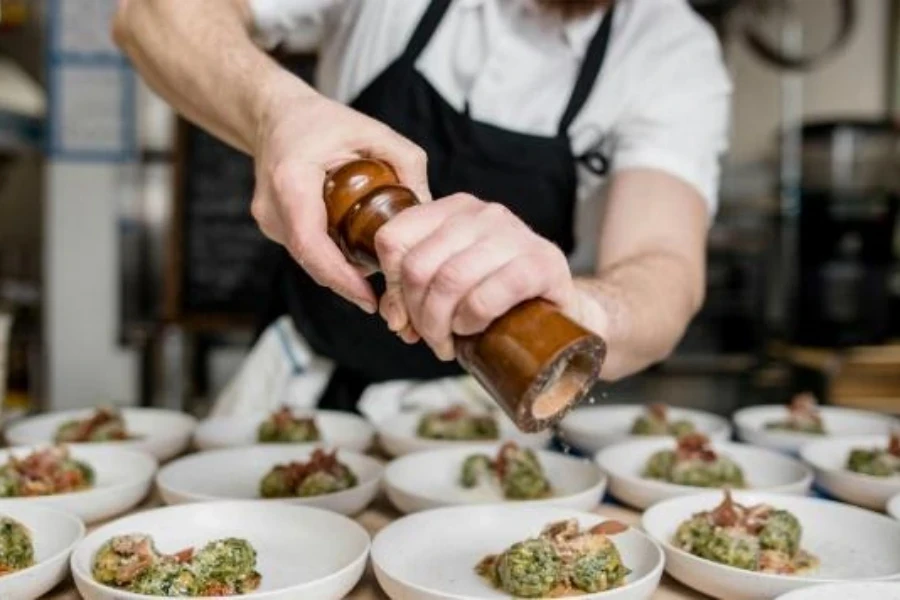 Chef using wooden pepper grinder