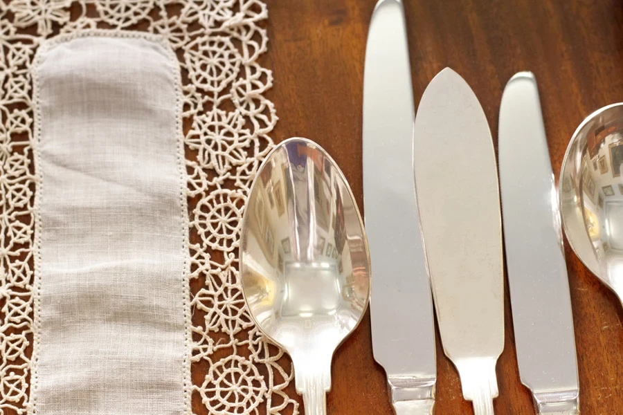 Collection of silver cutlery set out on wooden table