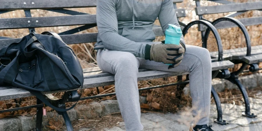 Crop unrecognizable male athlete sitting in park