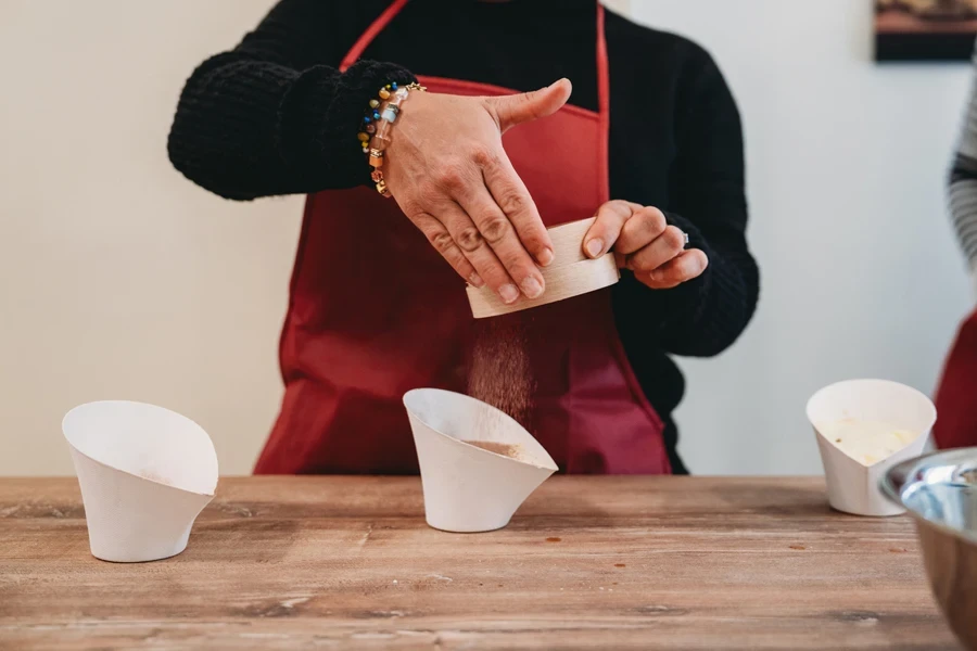 Female baker using round sifter with cocoa powder