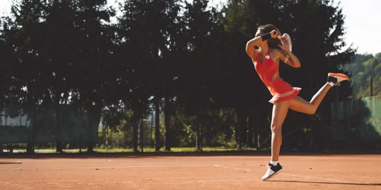 Tennisspielerin auf Sandplatz im roten Tenniskleid