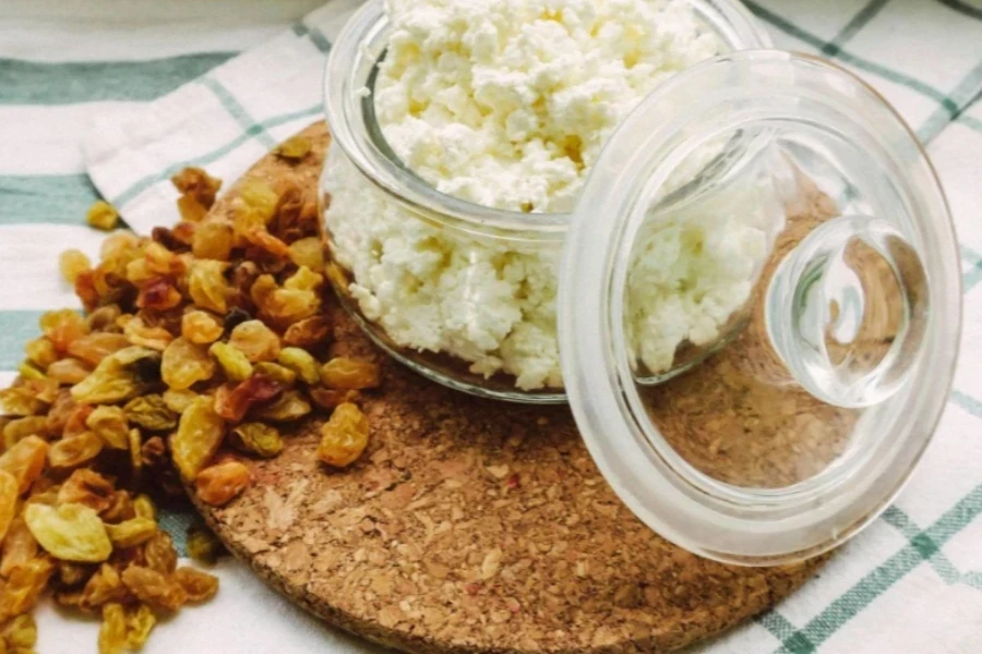 Glass container of cream cheese served with a cork trivet