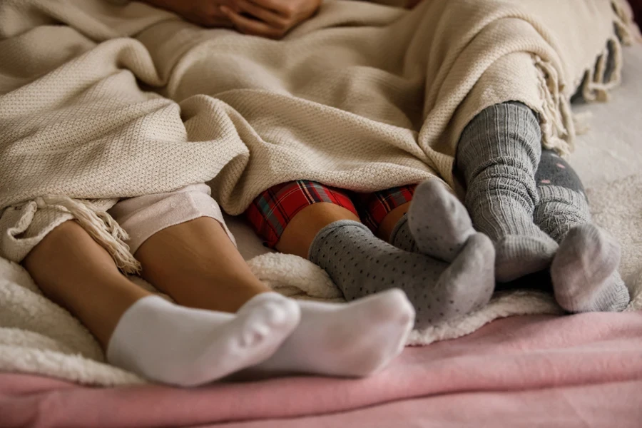 Ground of people wearing sustainable alpaca socks under blanket