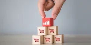 Hand arranging wood block stacking with icon Graph and shopping cart symbol upward direction