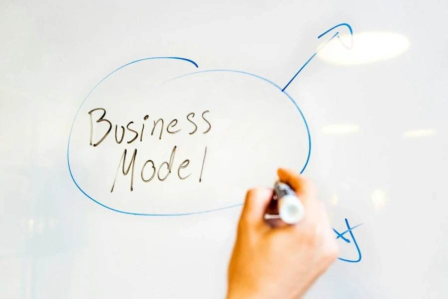 Hand holding marker pen writing ‘Business Model’ on white board