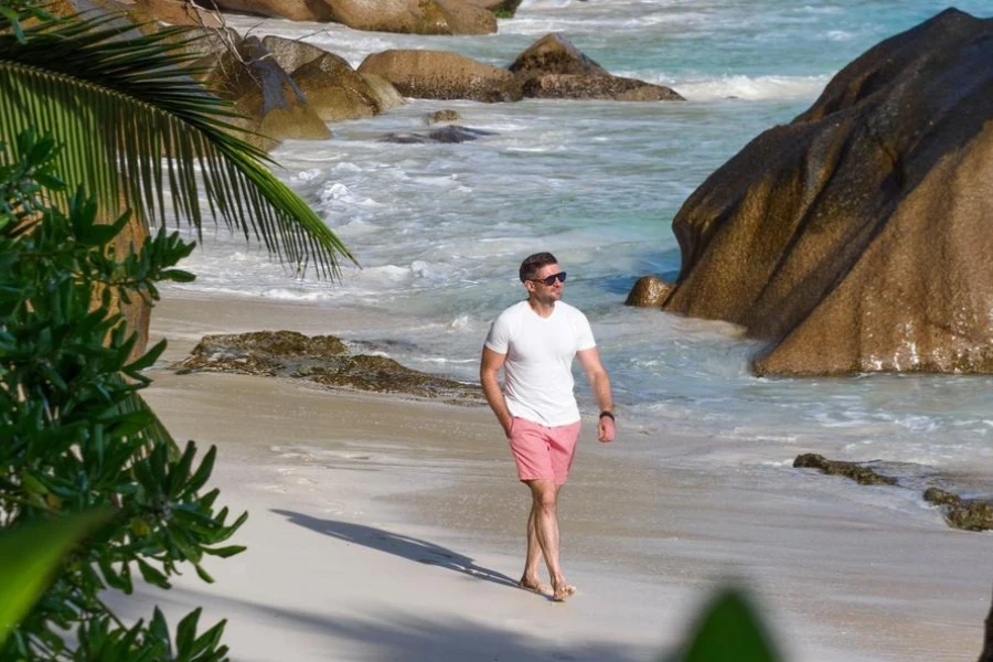 Handsome man walking on stunning white sand beach