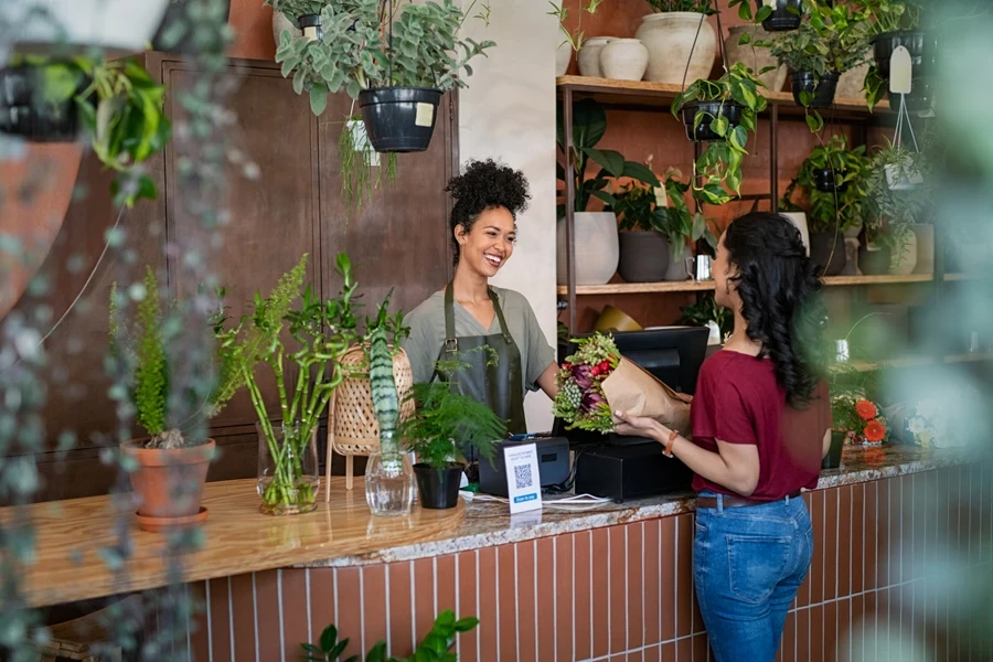Happy florist selling plants and flowers to client