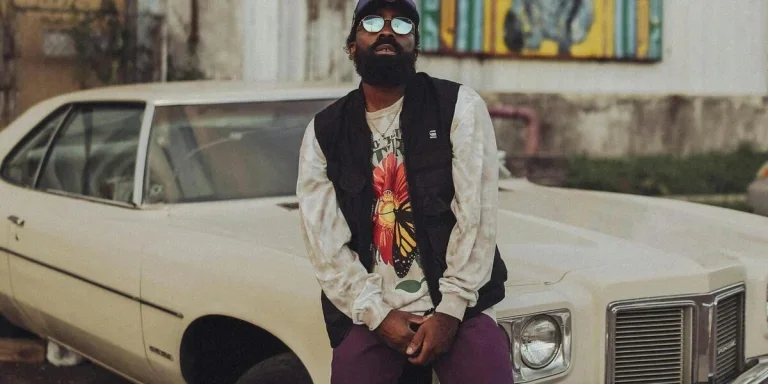 Man in streetwear posing with a white car