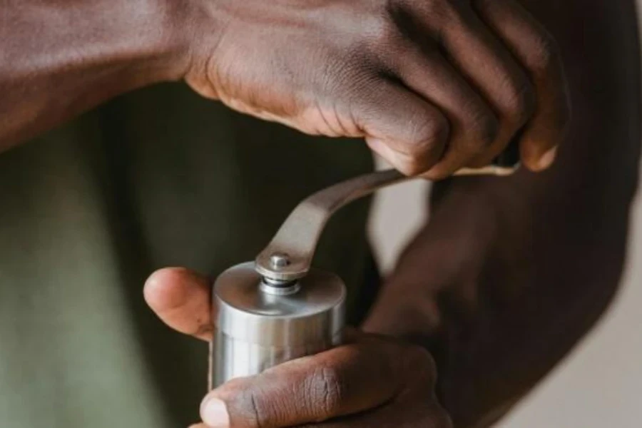 Man using stainless steel crank peppercorn mill