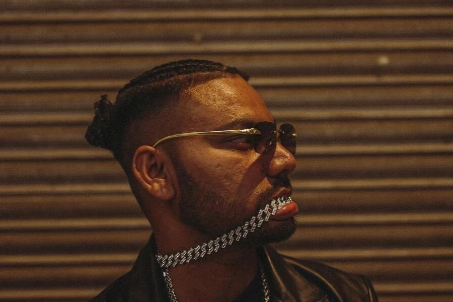 Man wearing glasses and a silver chain in his mouth
