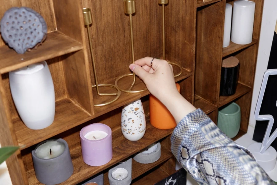Person arranging candles and candle stands on a shelf