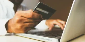 Person holding credit card over laptop