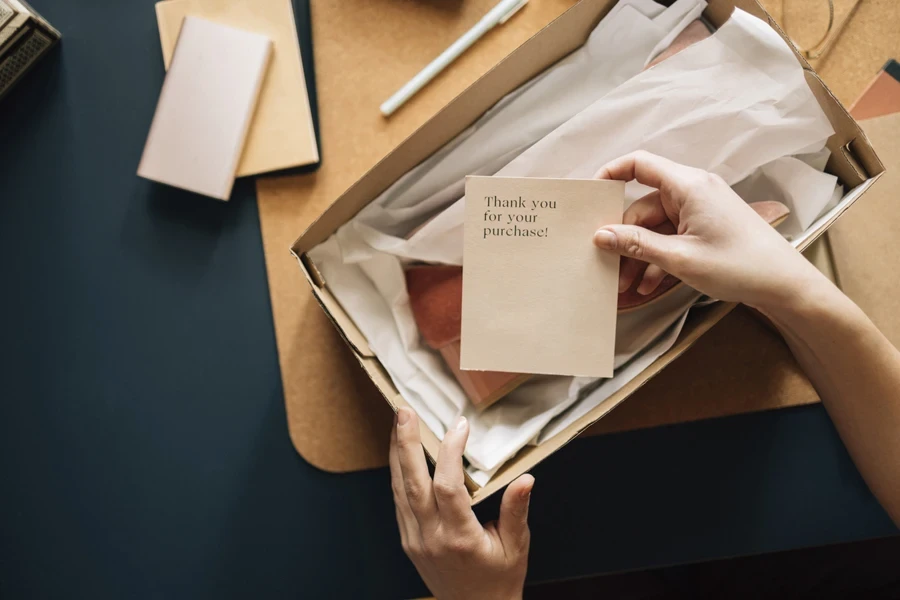 Person opening a package with a thank you note