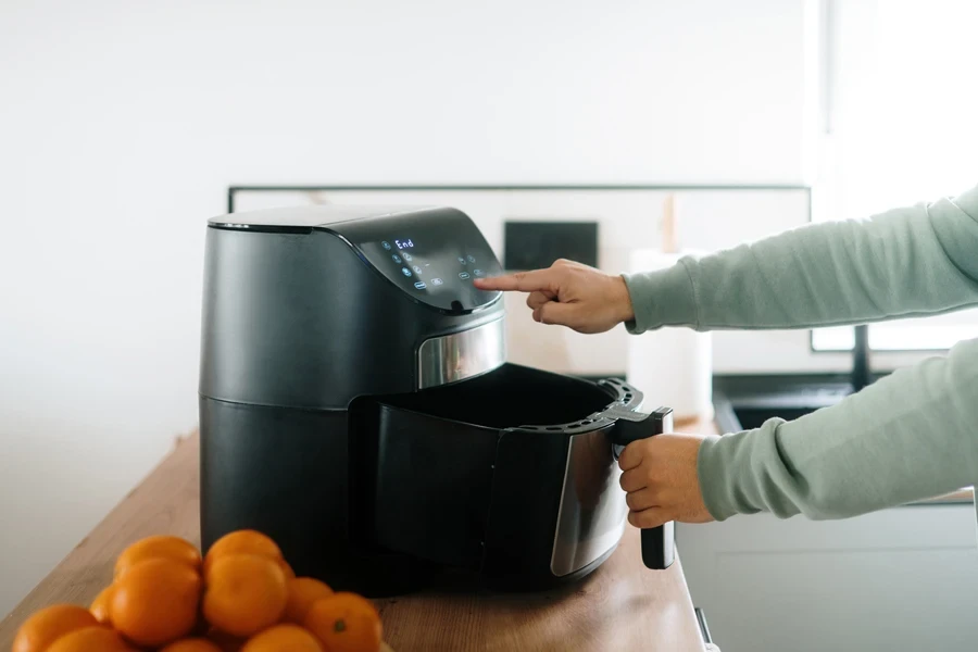 Person using a sleek black air fryer
