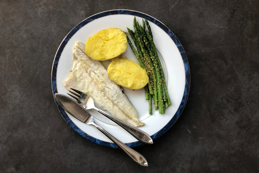 Plate with fresh white fish next to fish knife
