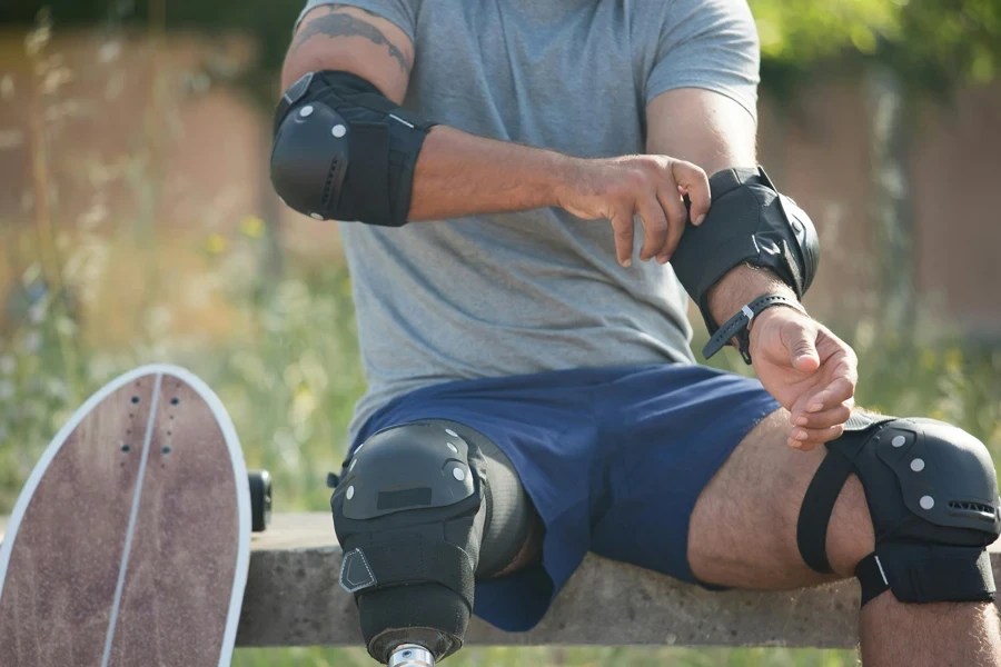 Skateboarder with prosthetic leg adjusts safety gear outdoors in Portugal