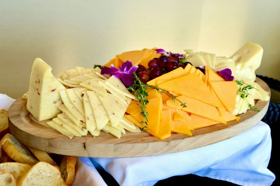 Thick wooden serving board with mixture of cheese on top