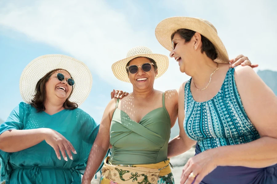 Three middle aged women wearing sunhats and a necklace