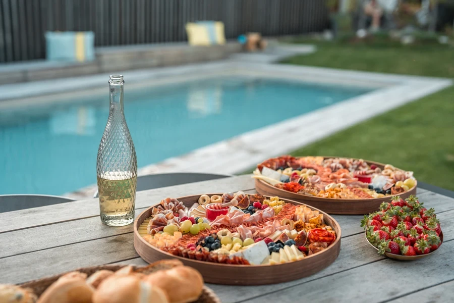 Two bamboo food platters next to pool and cups