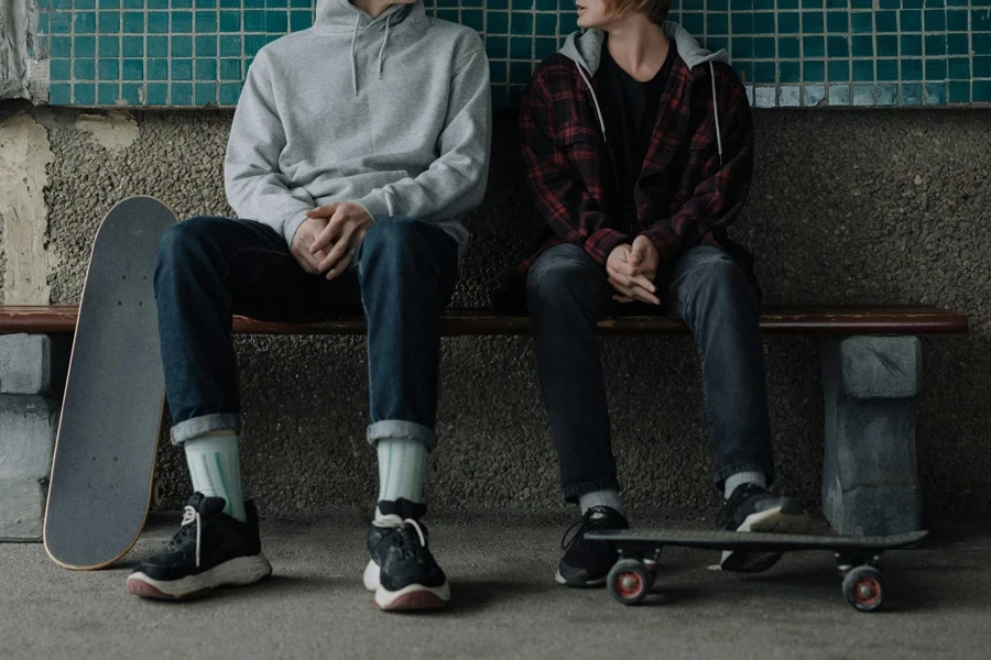 Two skateboarders sitting on a bench in a casual, urban setting