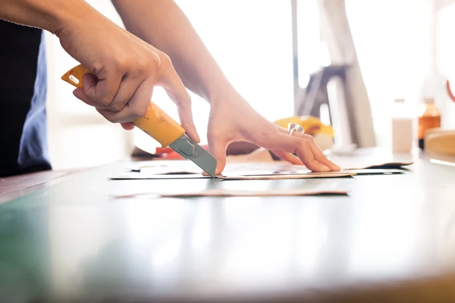 Utility knife being used to cut paper on table