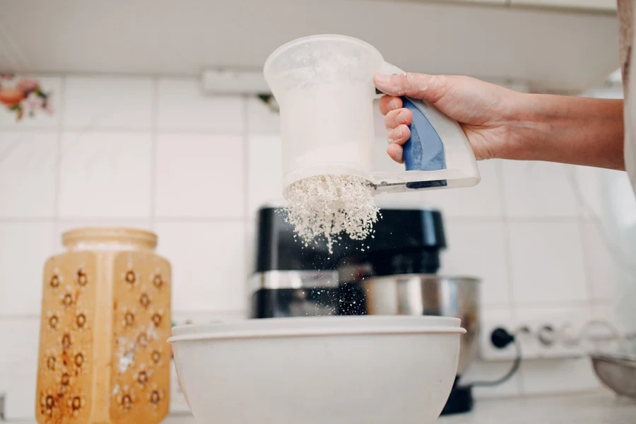 White battery-operated flour sifter held over white bowl
