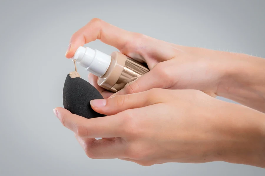 Woman applying skin tint on a makeup sponge