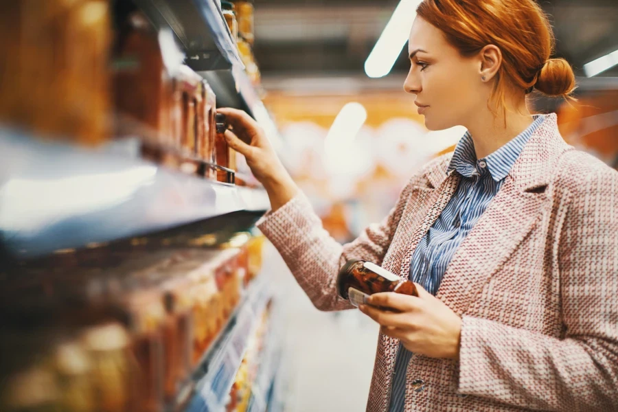 Woman comparing prices on a supermarket shelf