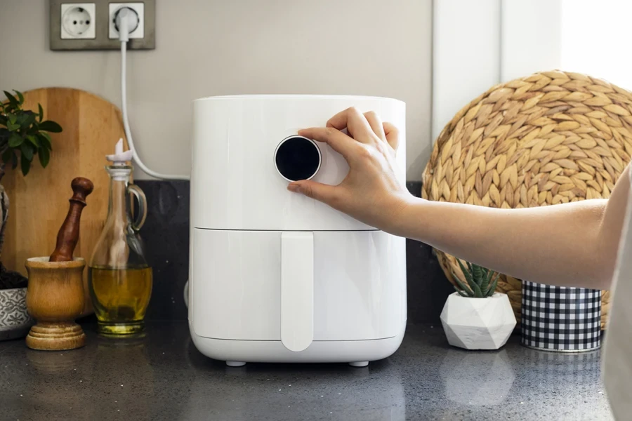 Woman controlling a modern air fryer’s temperature