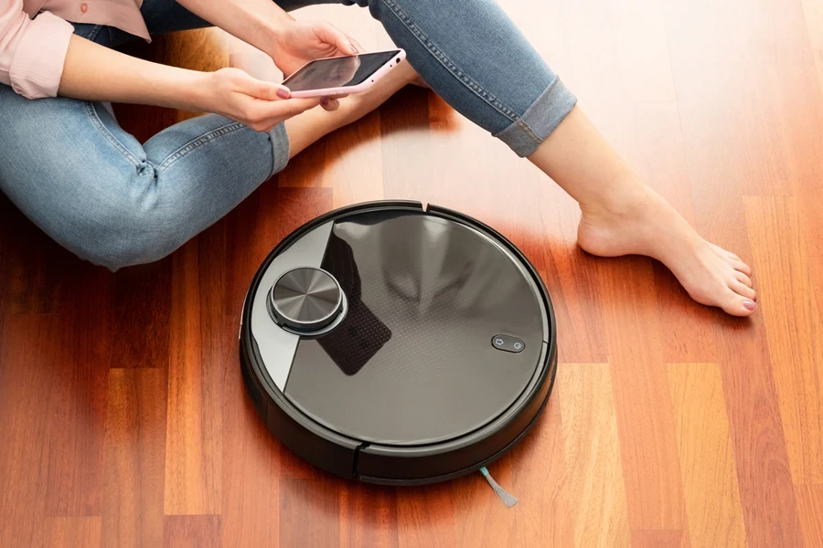 Woman controlling a smart vacuum cleaner with her phone