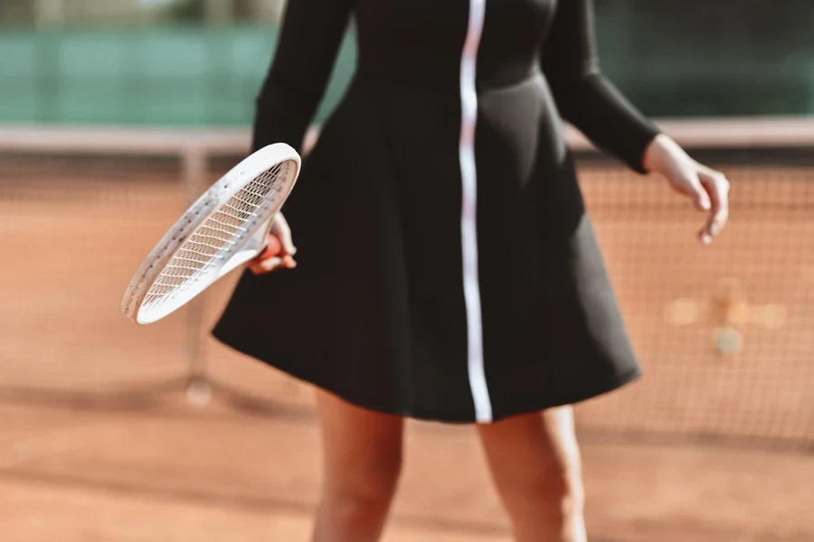 Woman holding white tennis racquet wearing black and white dress