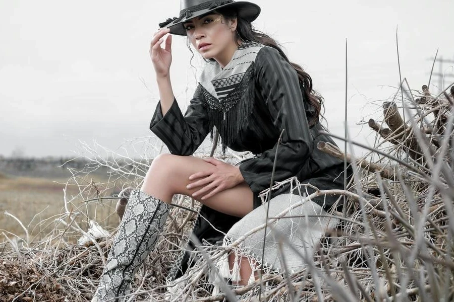 Woman in a cowgirl outfit sitting on a hay stack