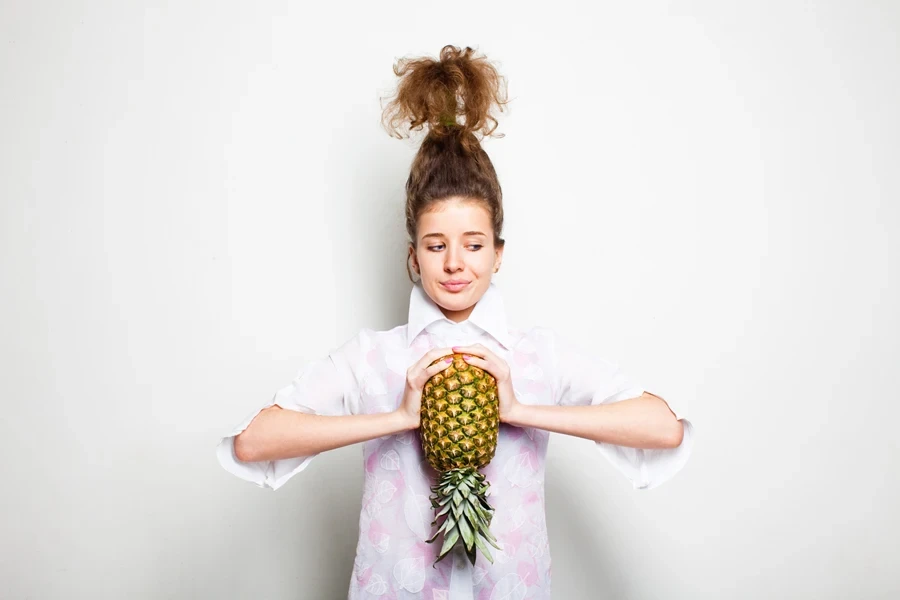 Woman rocking a pineapple updo holding a pineapple
