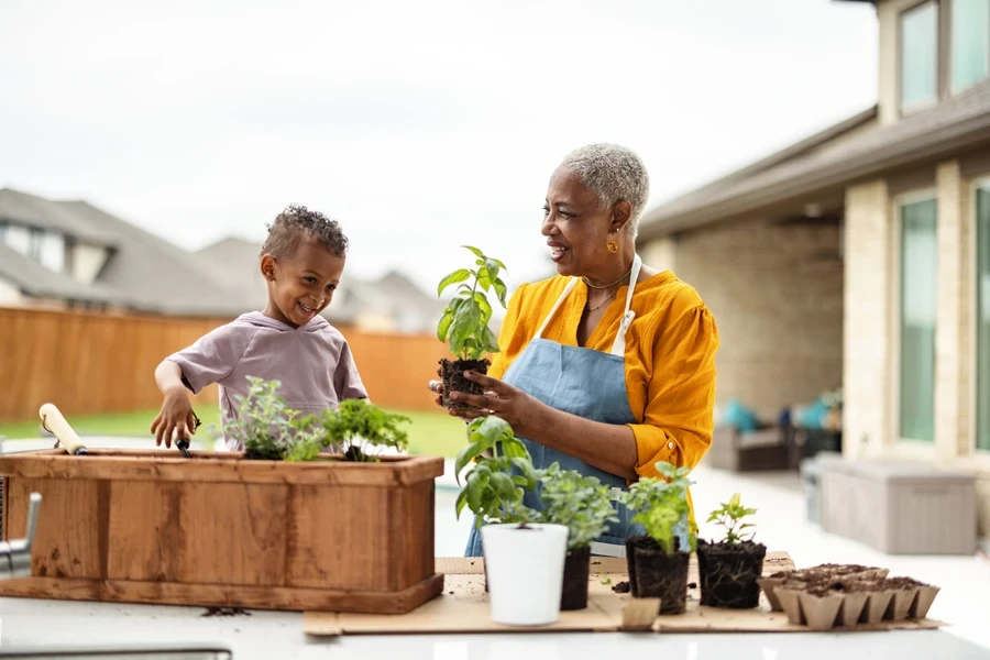 Woman showing grandson how to plant herbs in garden