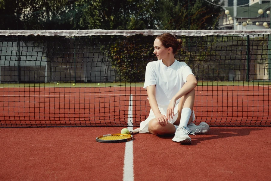 Woman sitting on tennis court wearing thermal tennis dress