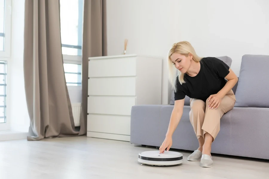 Woman using an automatic vacuum cleaner