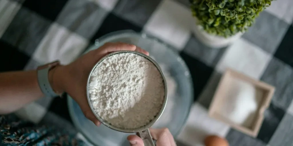 Woman using stainless steel sifter with flour powder