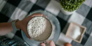 Woman using stainless steel sifter with flour powder