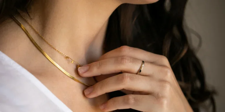 Woman wearing gold ring touching gold snake necklace