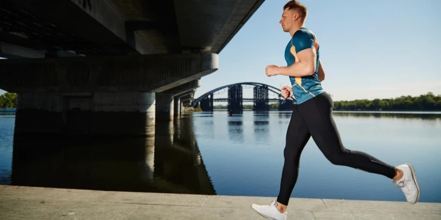 Young handsome man running under the bridge