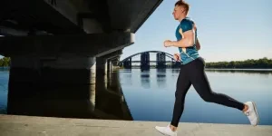 Young handsome man running under the bridge