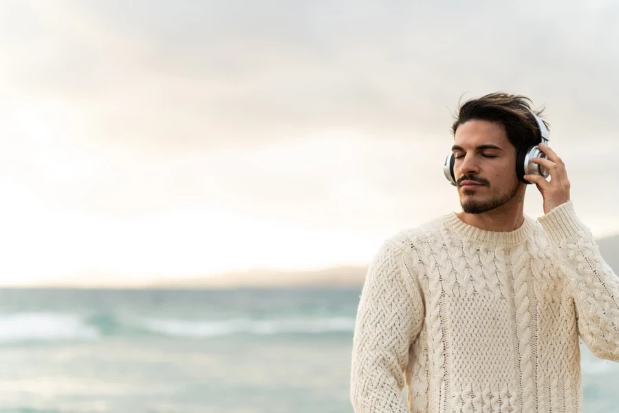 Young man in knotted shirt listening to music