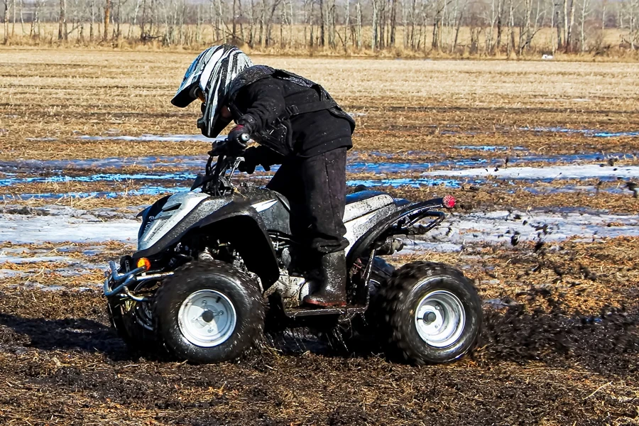 Young rider riding an ATV on mud