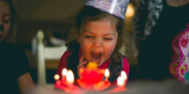Fotografía de enfoque superficial de un niño pequeño soplando velas de pastel