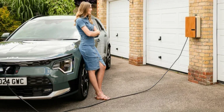 Una señora cargando su coche con un cargador doméstico para vehículos eléctricos.