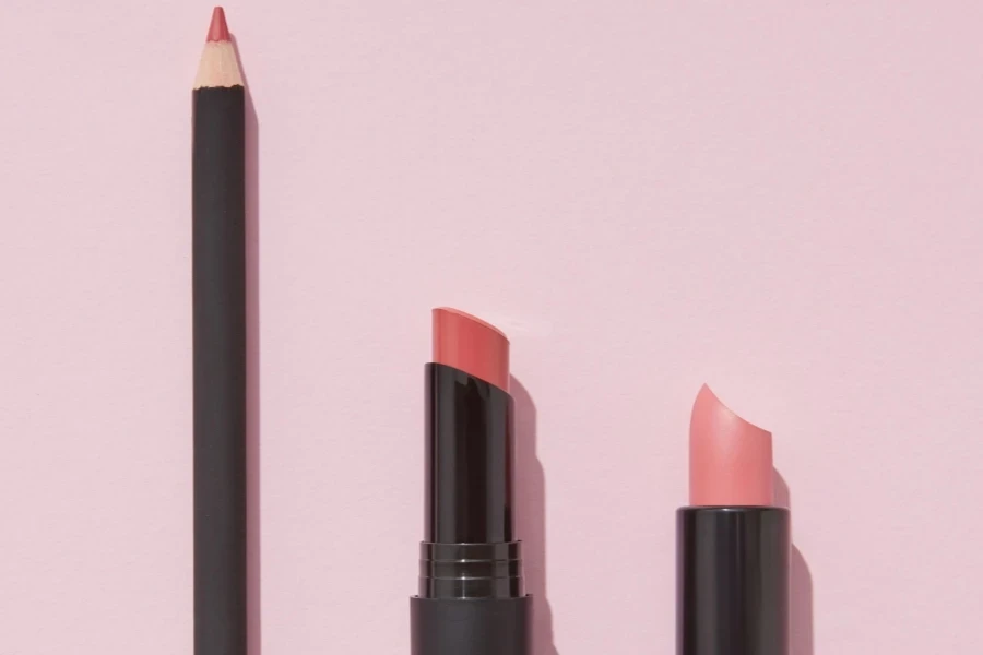 A lip liner and two lipsticks against a pink background