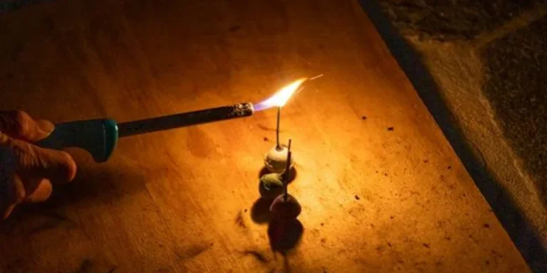 Зажженная спичка, удерживаемая зажигалкой