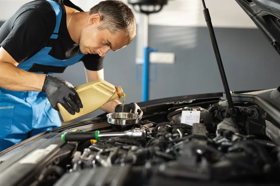 A mechanic pouring synthetic oil into an engine